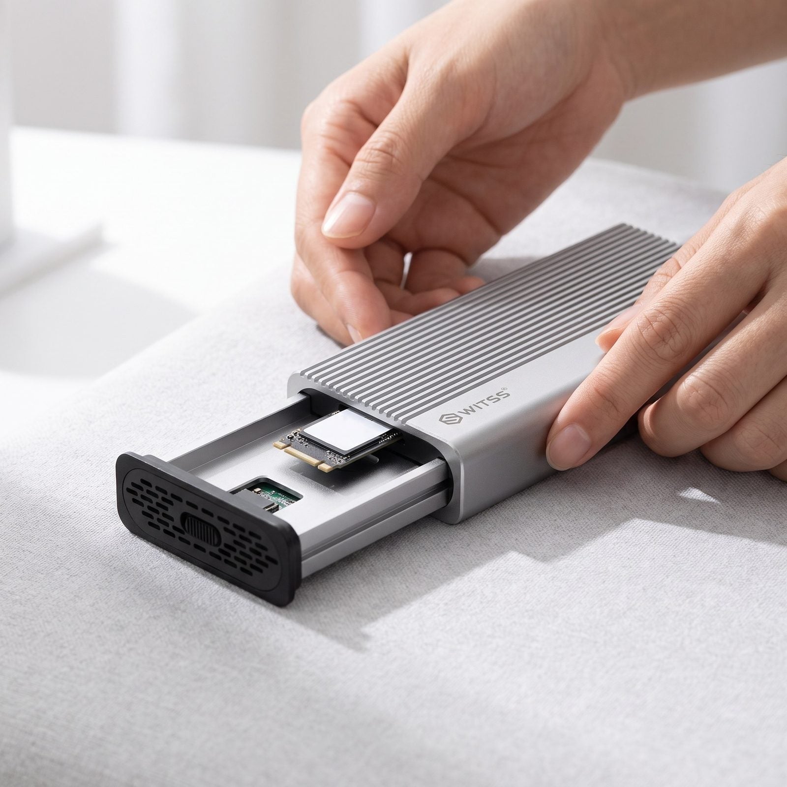Handen die een M.2 SSD-kaart in een Switss® behuizing schuiven