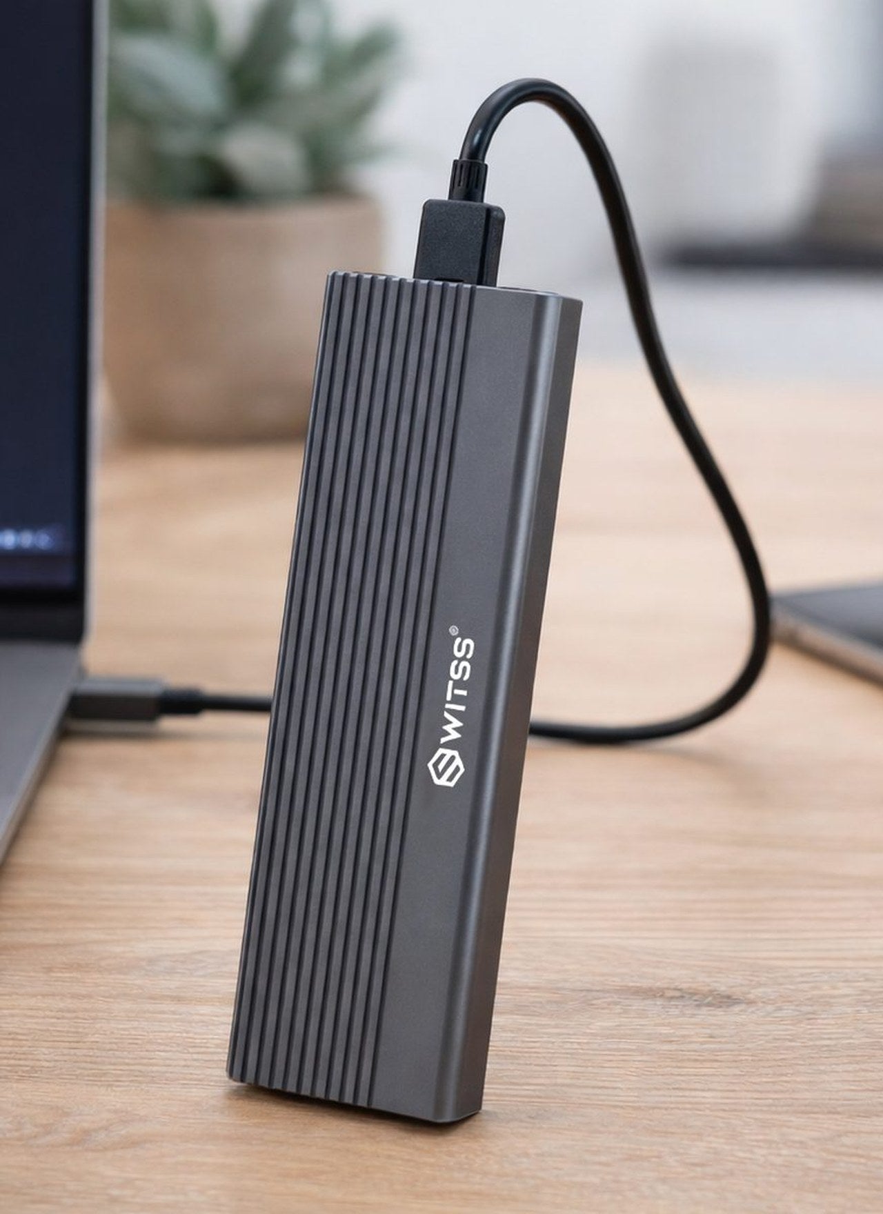 Switss® M.2 SSD behuizing op een bureau, met een USB-C-kabel aan een laptop