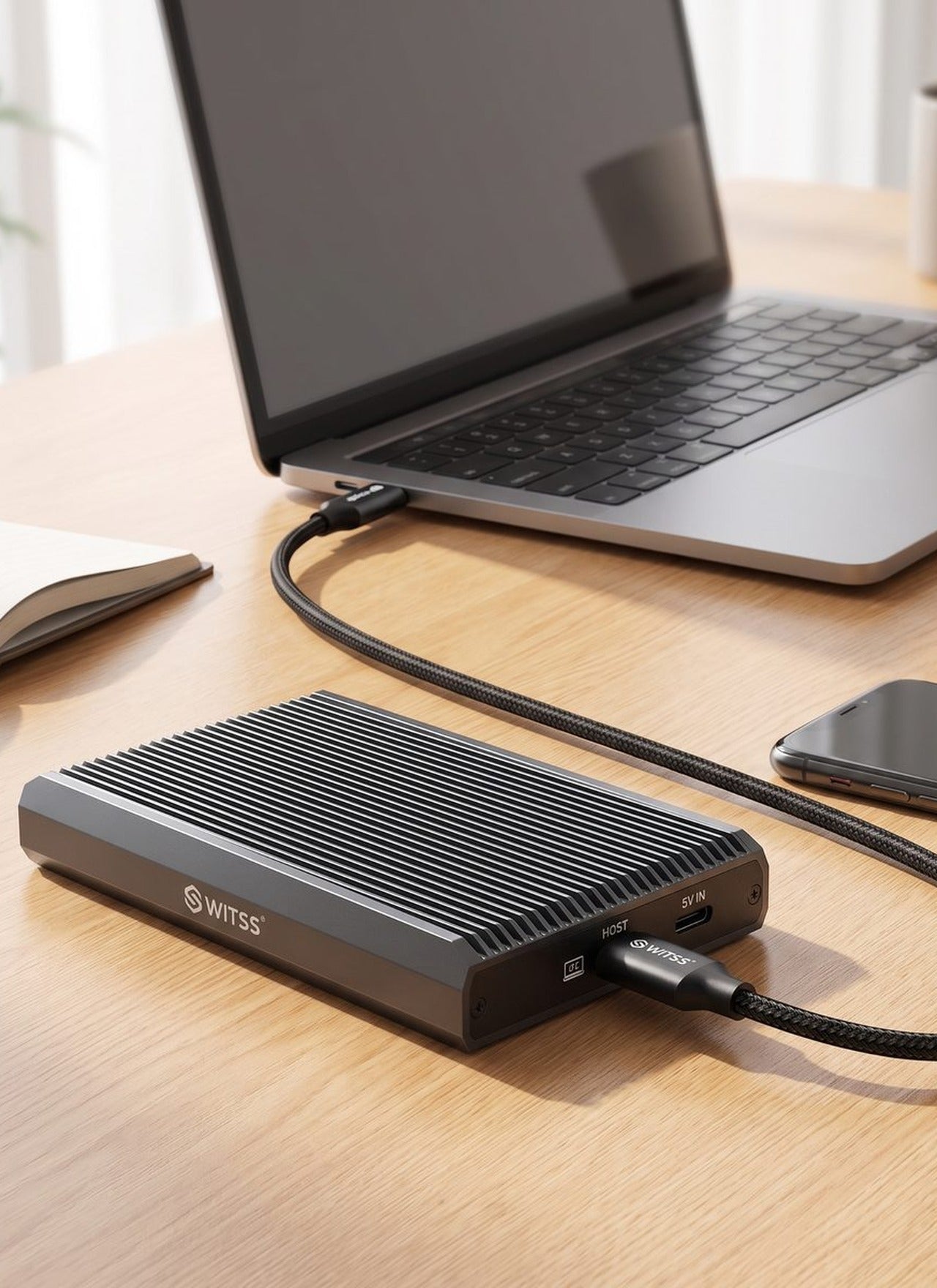 Switss® RAID Dual-Bay M.2 behuizing op een bewerkingsbureau naast een laptop