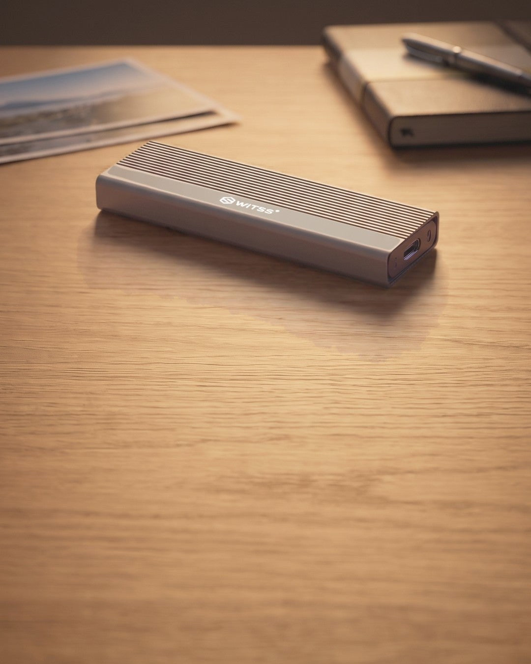 Switss® M.2 SSD-behuizing op een bureau naast afgedrukte familiefoto's