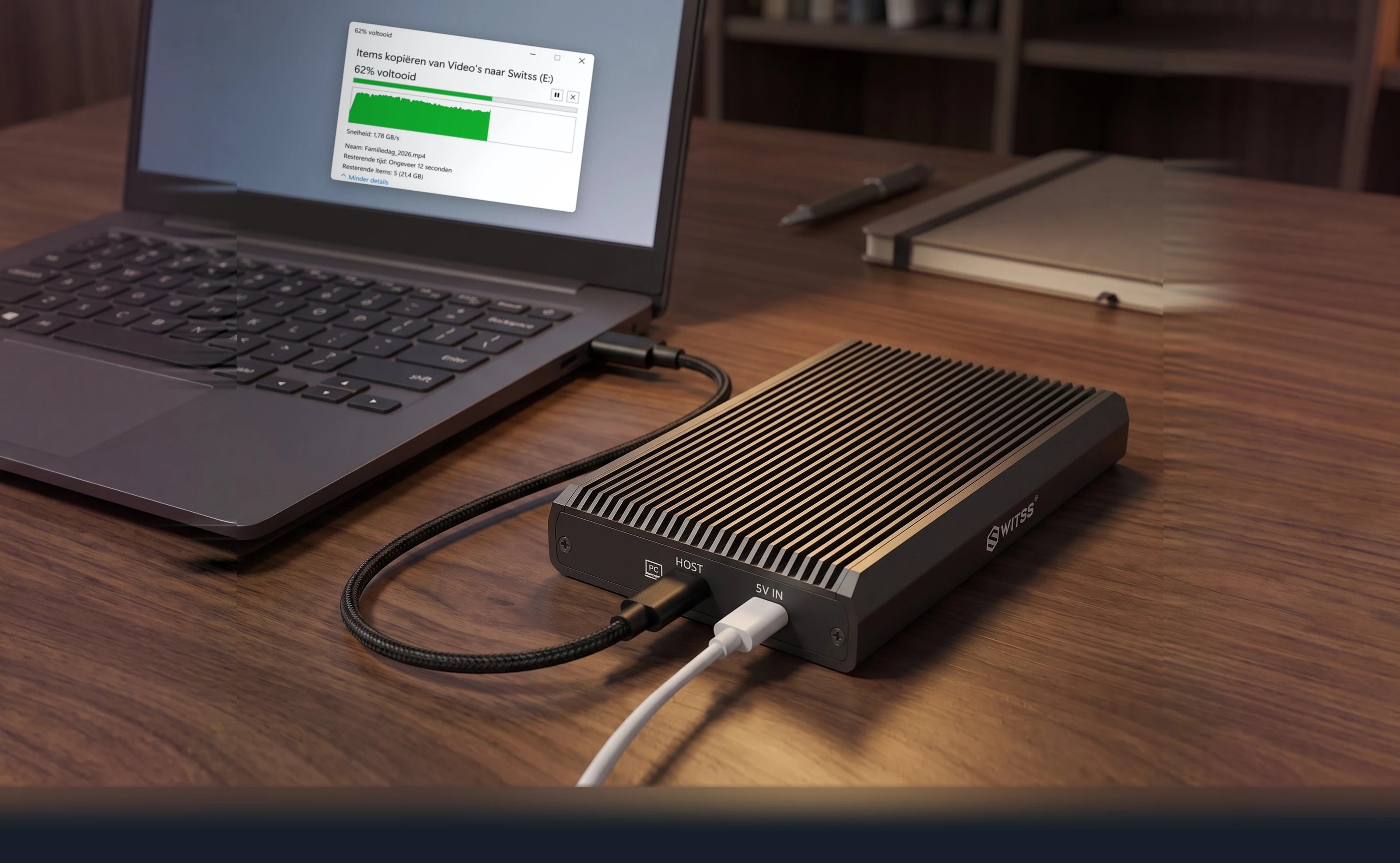 Switss® RAID dual-bay behuizing op een walnoten bureau, met de kabel naar een laptop waarop een kopieervenster openstaat