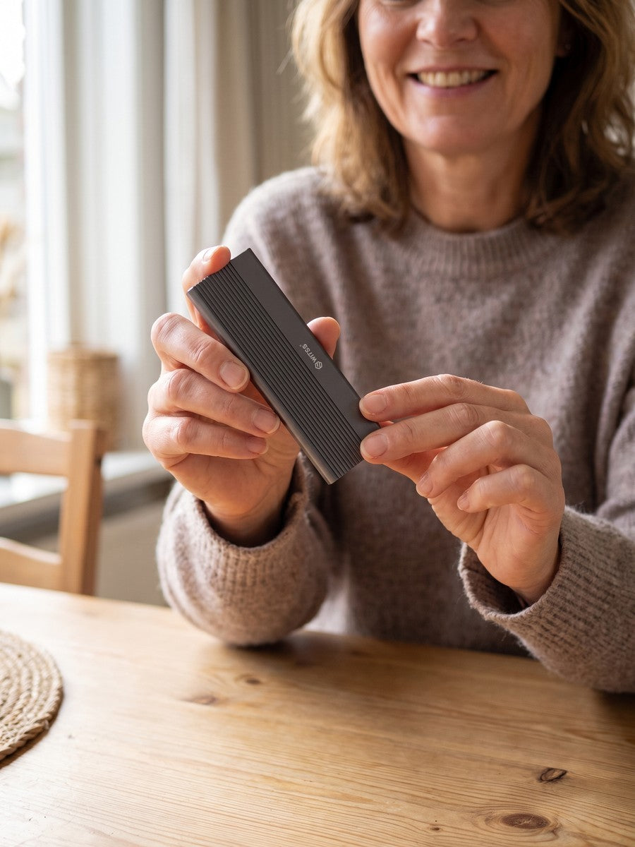 A woman holds the Switss M.2 enclosure, aluminium cooling fins visible